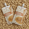 Cashew caramel nut butter to-go 2oz pouches by Nut Dreamers on a bed of whole cashews — no palm oil no added sugar
